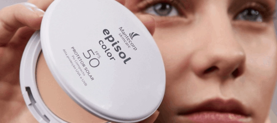 Mulher segura protetor solar em pó Episol Color FPS 50 próximo ao rosto