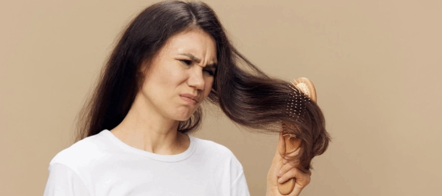 Mulher expressa insatisfação e dificuldade para desembaraçar o seu cabelo.