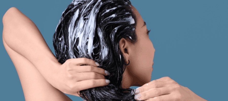 mulher aplicando condicionador com ácido hialurônico no cabelo.