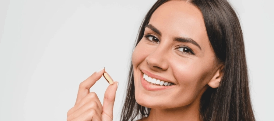 ma730 - Mulher sorri e segura cápsula enriquecida com vitaminas para a pele