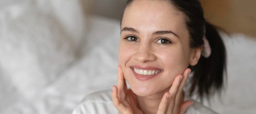 mulher com cabelos presos cuidando da pele do rosto em casa