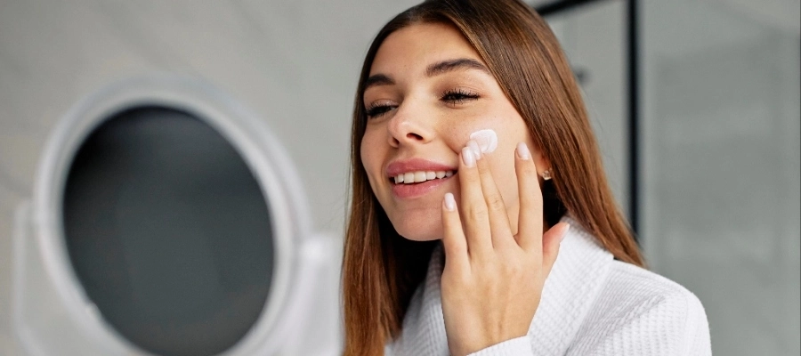 Mulher aplica creme no rosto e testa para que serve o hidratante restaurador