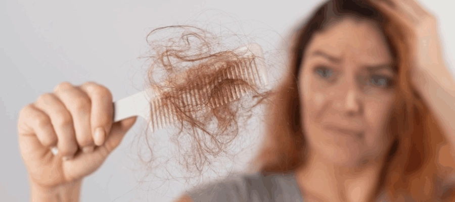 Mulher sorri e segura escova de cabelo redonda, balançando os cabelos soltos e ondulados.